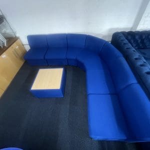 A blue modular corner settee with a square wooden coffee table in the center, top view
