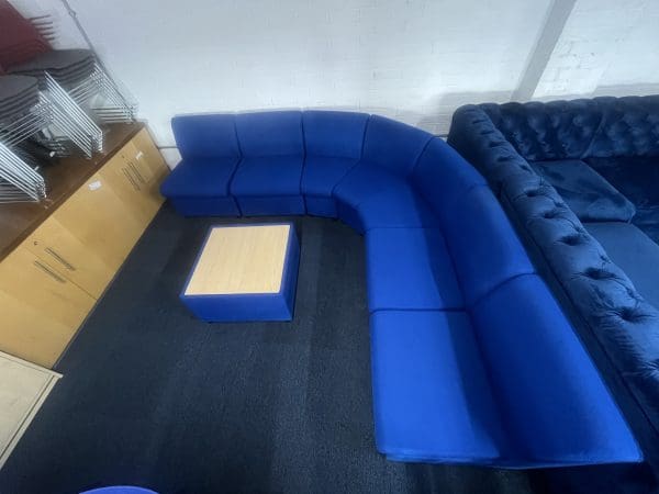 A blue modular corner settee with a square wooden coffee table in the center, top view